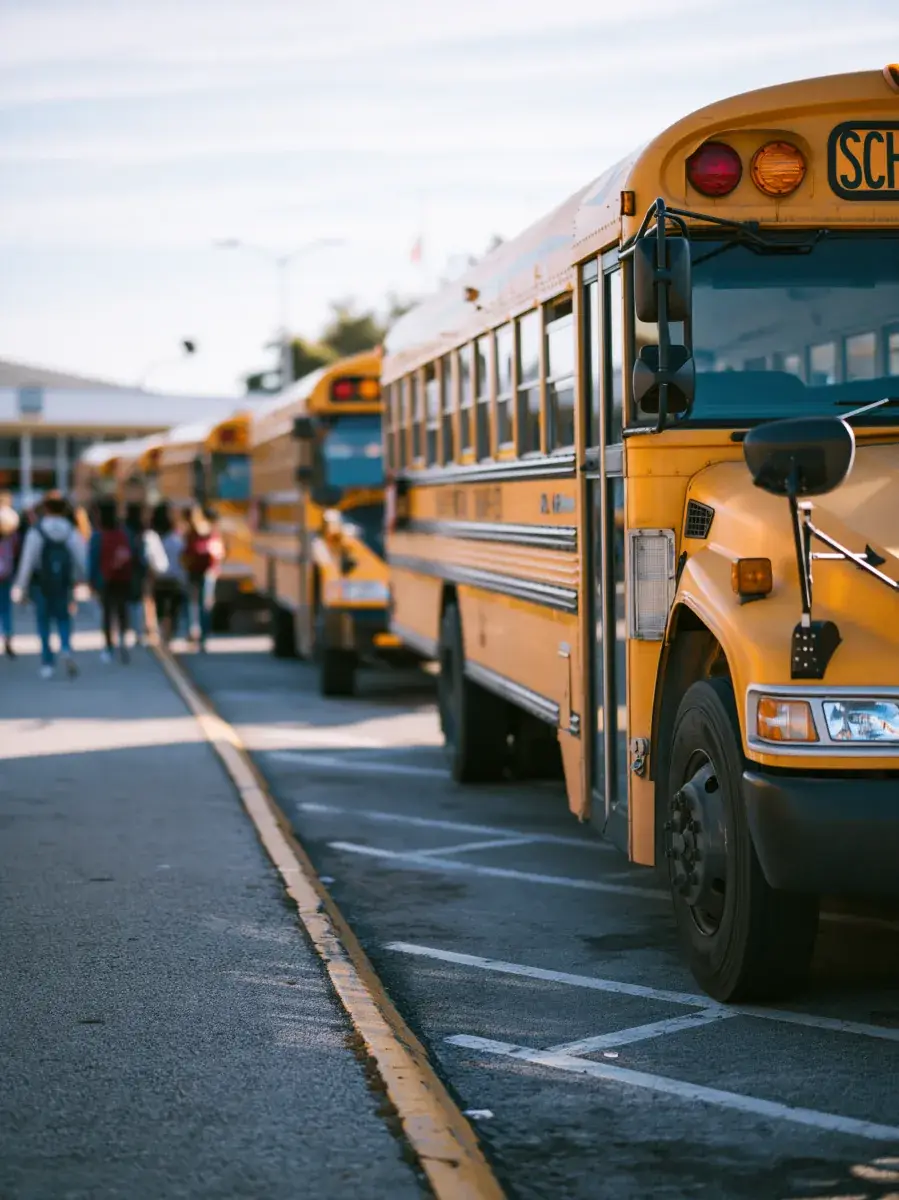 Buses nose-to-tail along the school loop, riders queued at the far end.